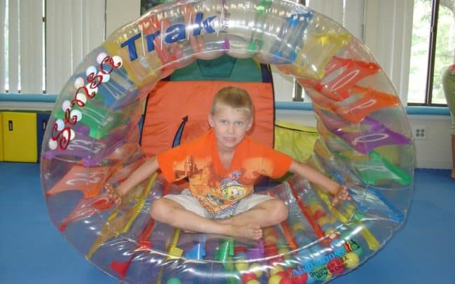 kid sitting in tube toy